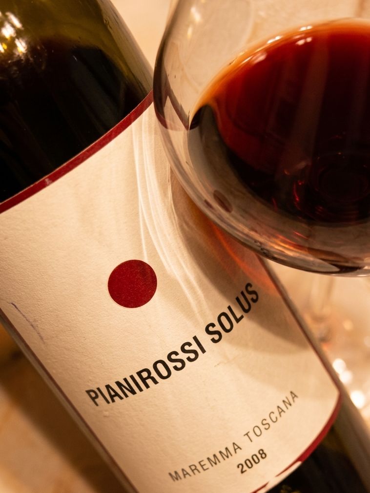 Una bottiglia di Solus Pianirossi 2008 insieme ad un calice dal quale si nota il colore